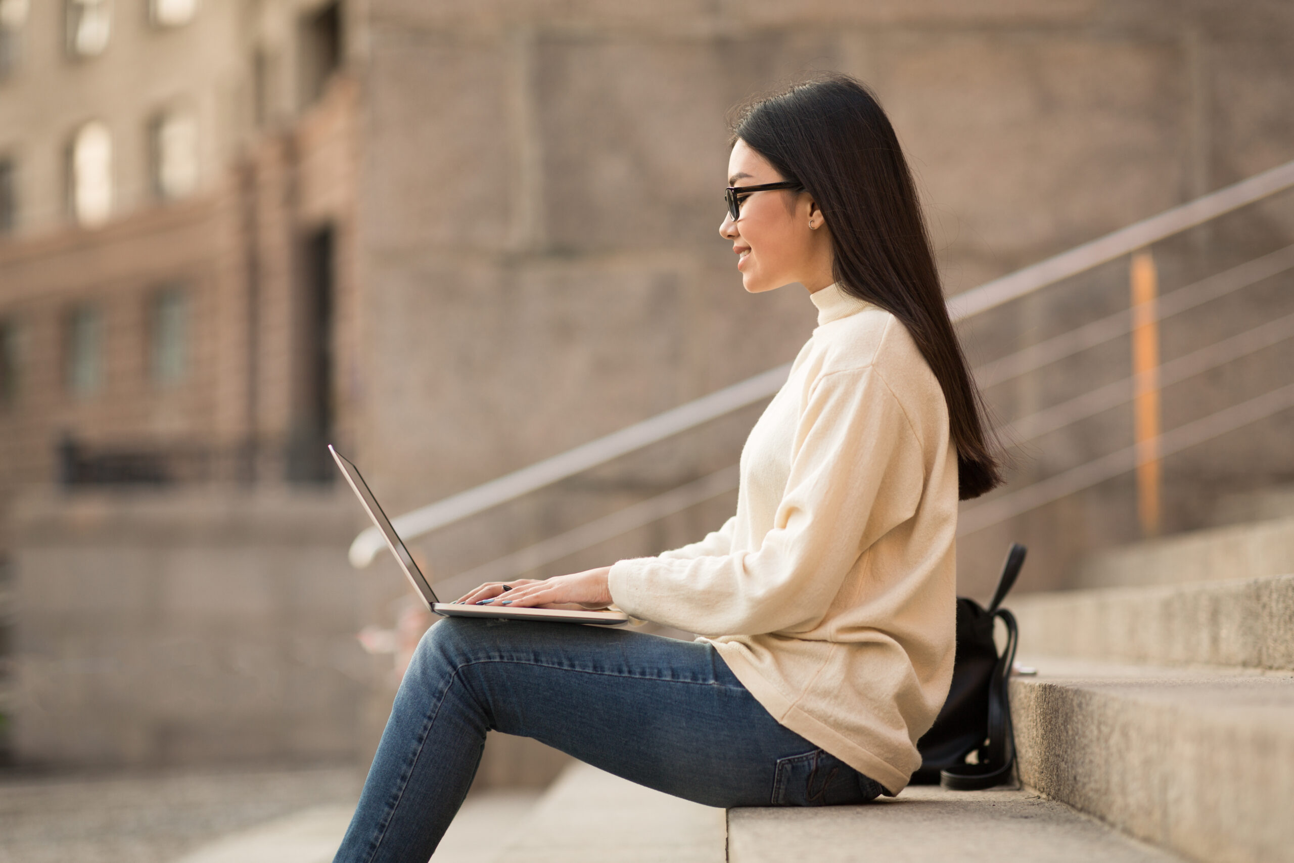 Student in Specs using laptop sitting on stairs